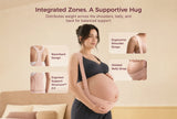 Pregnant woman wearing the oyster pink Momcozy maternity support band with racerback straps in a bedroom.