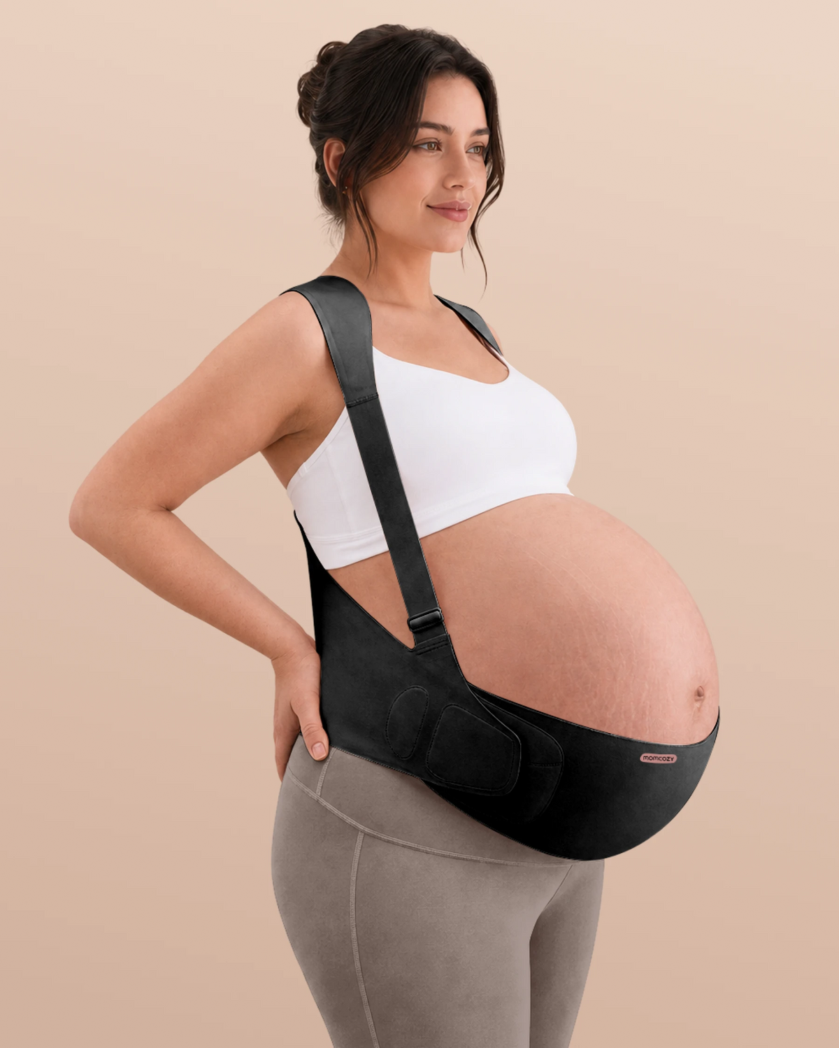 Pregnant woman wearing the oyster pink Momcozy maternity support band in a three-quarter view.